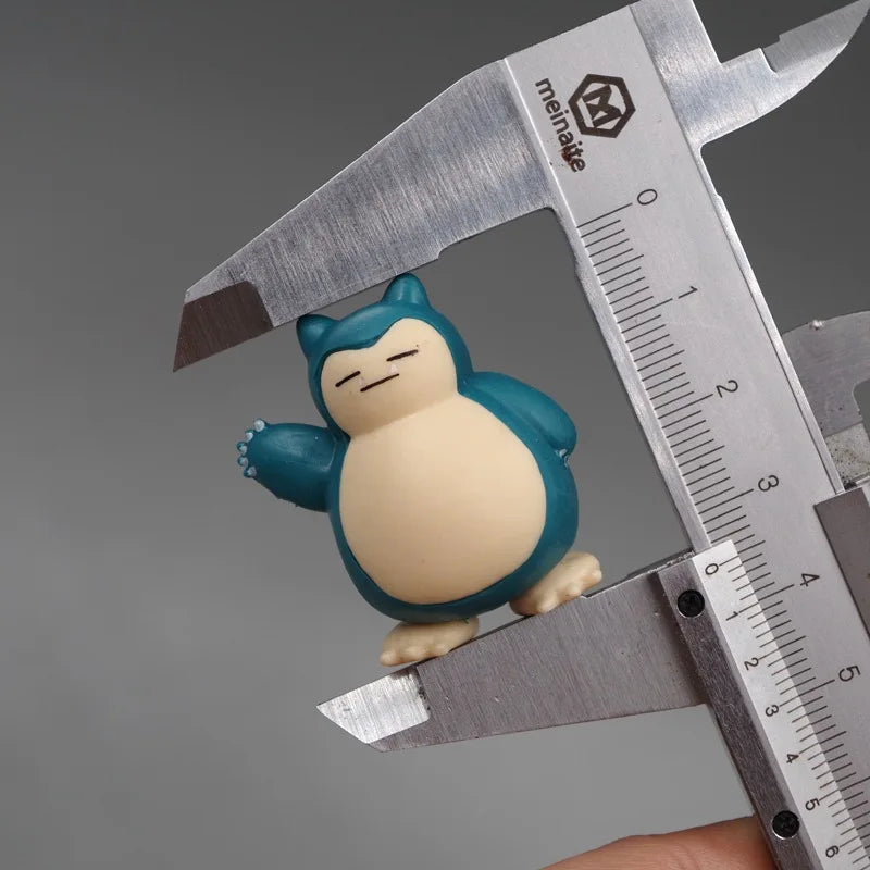 Close-up of a tiny Snorlax figurine being measured with calipers, highlighting its small size and detailed design, against a neutral gray background.